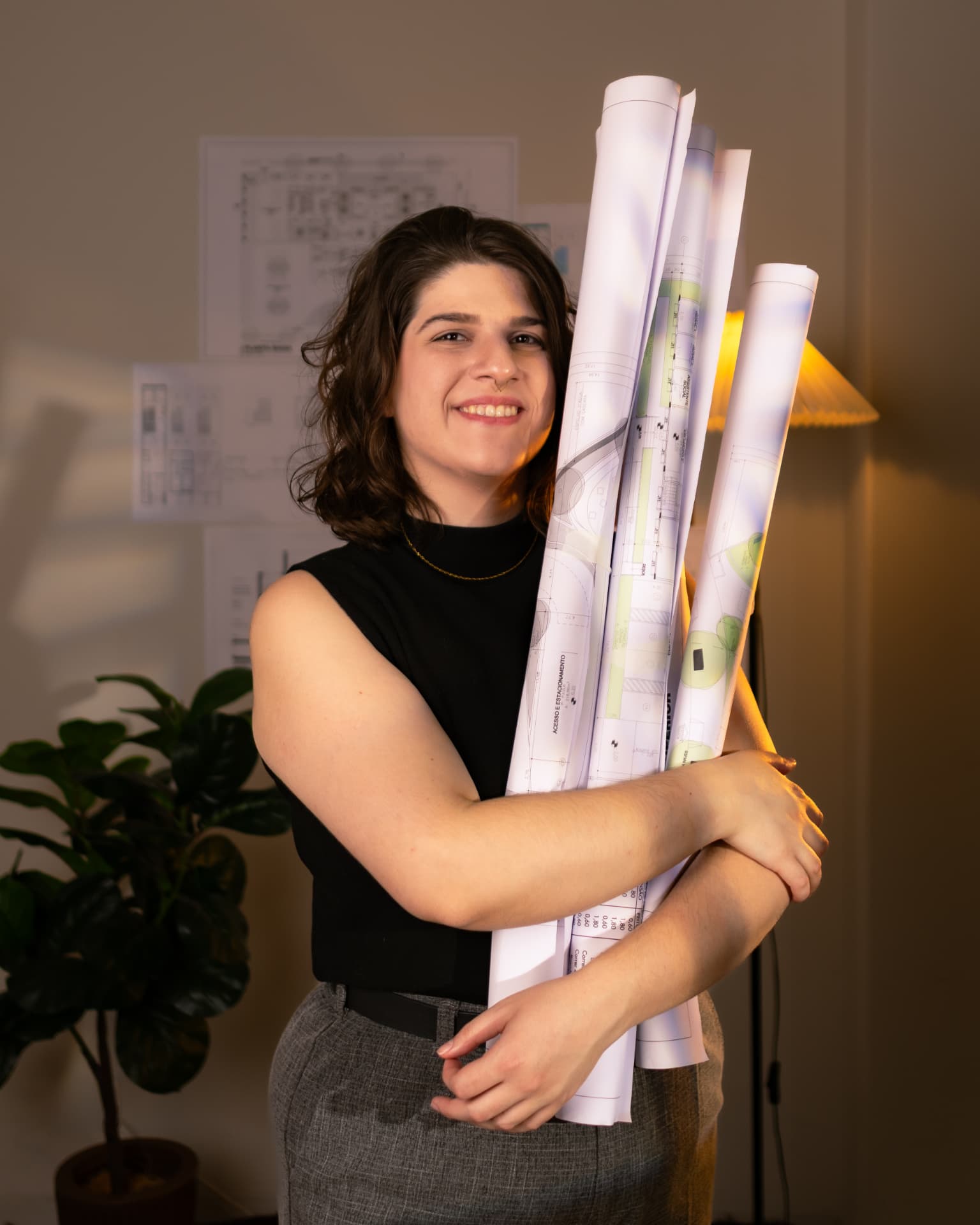 Luana Obici sorrindo enquanto segura pranchas de projetos arquitetônicos