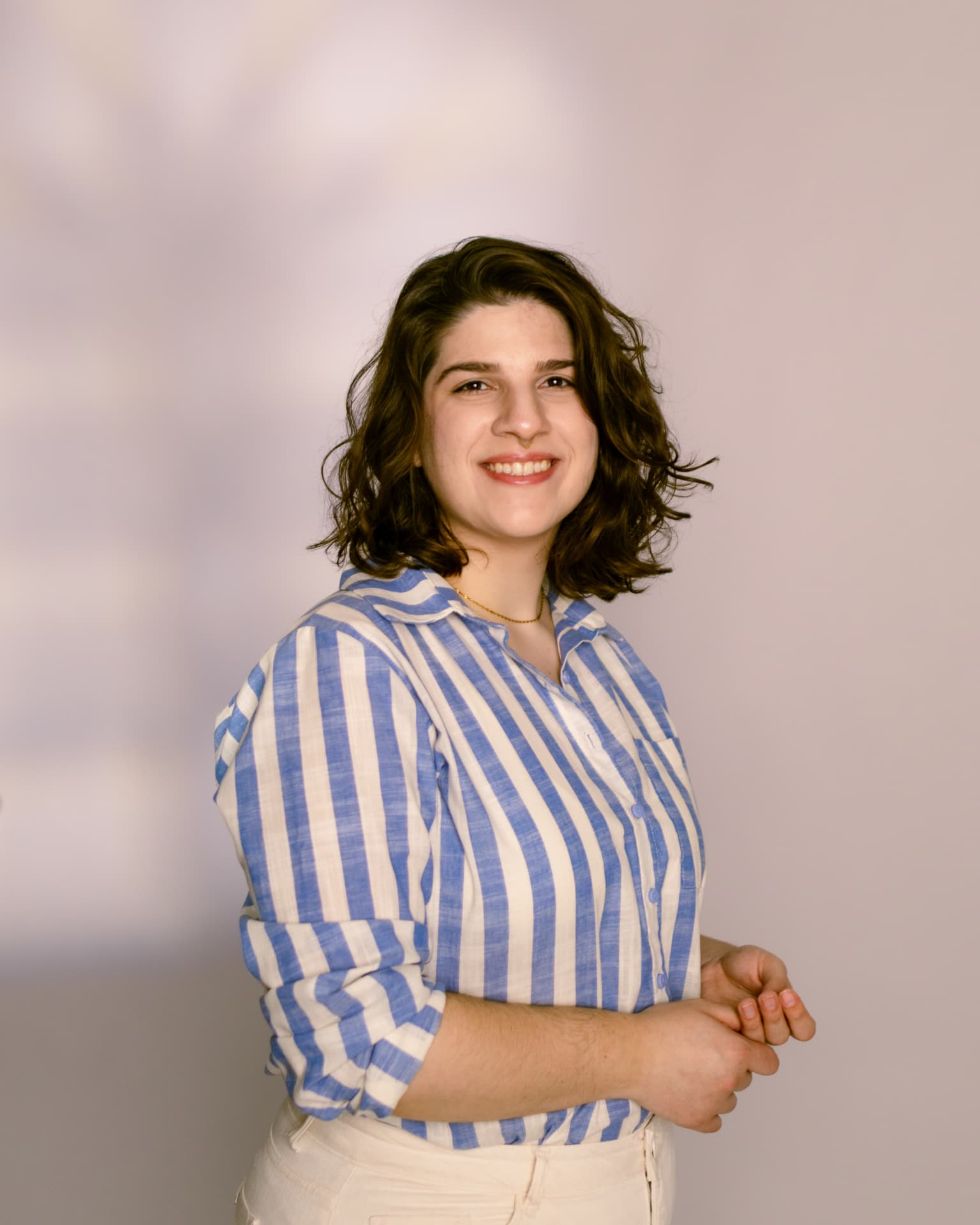 Luana Obici sorrindo em retrato com camisa listrada azul e branca